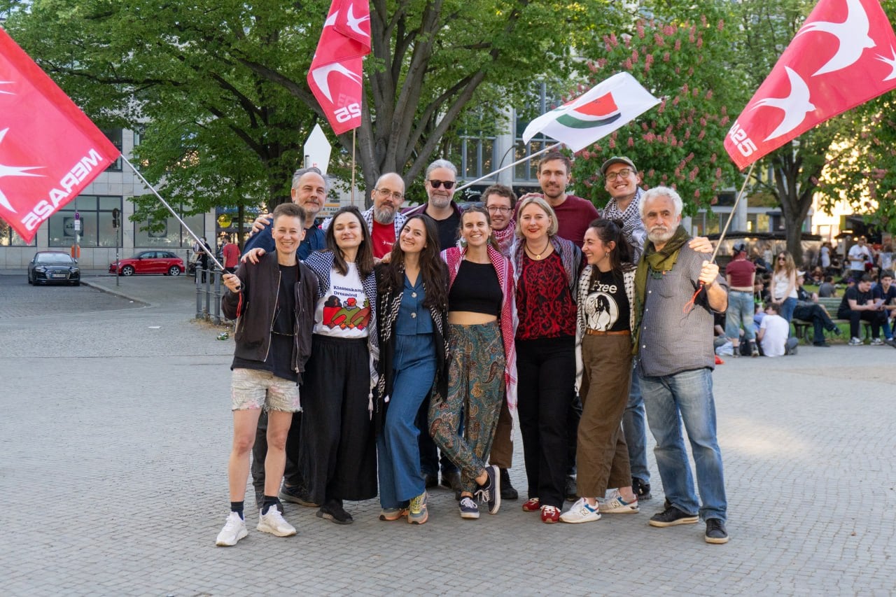 MERA25-Aktive mit MERA25- und Palästina-Fahnen auf einem Platz in Berlin